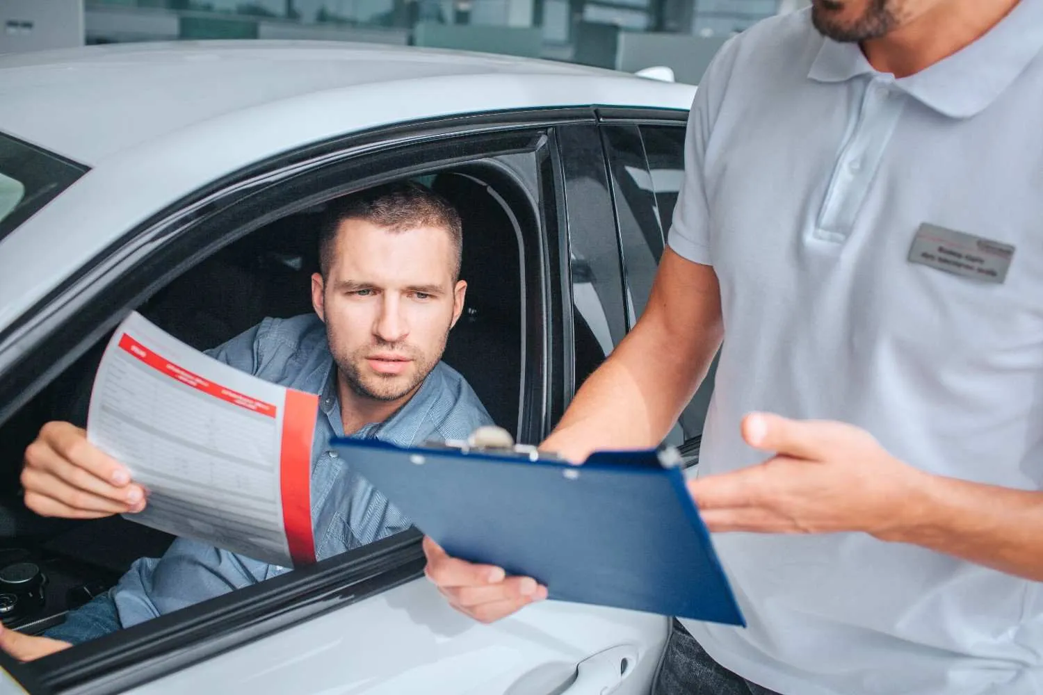 Driver going over a document with a man holding a clipboard beside the car